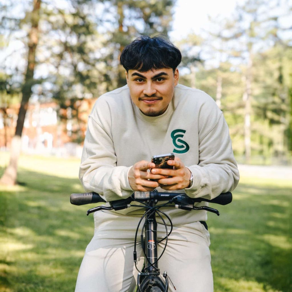 Un étudiant avec son téléphone dans les mains regarde la caméra